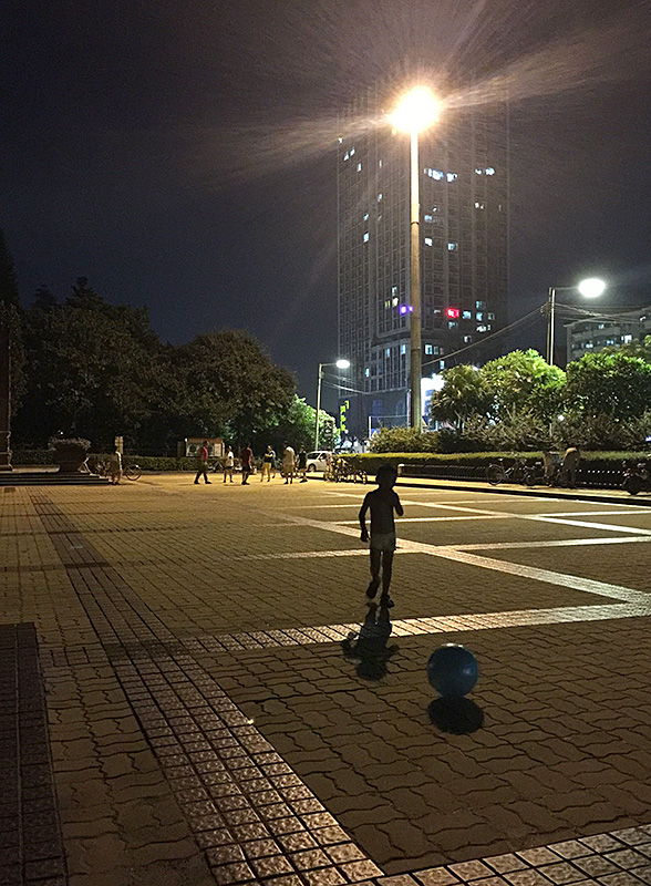 广州公园一角光着膀子的小孩正在玩球